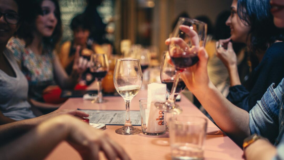 pexels-photo-696218-696218 A lively scene of friends enjoying wine and conversation in a cozy bar setting.